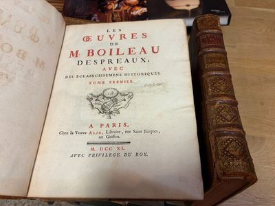un livre ouvert posé sur une table, à côté d'autres livres