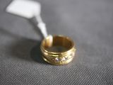 a gold wedding ring with diamonds on a gray surface
