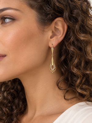 La femme porte une chemise blanche et des boucles d'oreilles dorées.