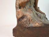 a bronze statue of a woman sitting on a rock