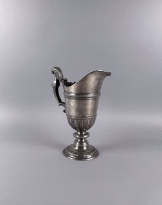 an antique silver plated pitcher on a pedestal with a handle