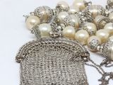 a silver purse with pearls and a chain around it