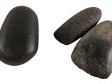 three black rocks sitting next to each other on a white surface