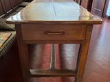 a wooden table with a drawer on it in the corner of a room