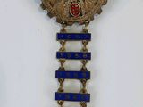 a close up of a blue and gold broochle on a white surface