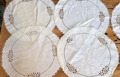 six white doily placemats on a wooden table
