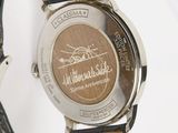 the watch has a brown dial and black leather strap
