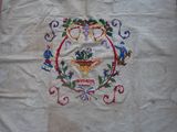 an old embroidered table cloth with a design of grapes and flowers