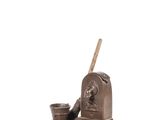 bronze statue of a man with a hat and a cup on a table