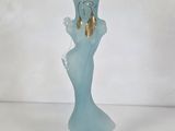 a blue glass vase with a gold bell on it