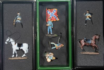 four miniature figurines of soldiers and horses in a display case