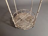 a metal basket with bamboo sticks in it on a table