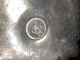 a silver vase with a coin in it on a black background
