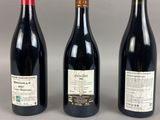 three bottles of wine are lined up on a table
