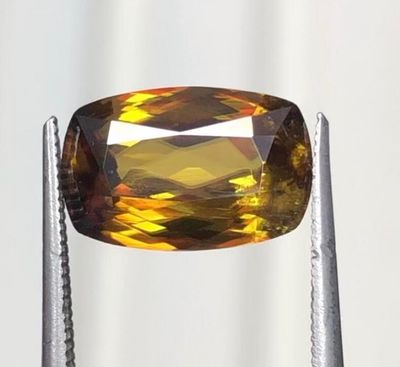 un gros plan d'un diamant jaune tenu par une paire de pinces