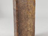 an old book sitting on top of a white table next to a cup