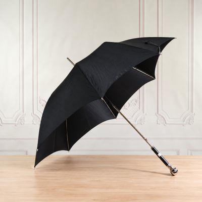 an open black umbrella sitting on top of a wooden floor