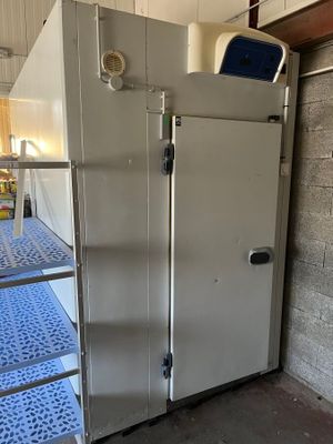 un réfrigérateur qui se trouve dans une pièce où il y a une échelle