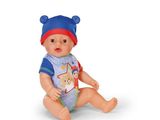 une poupée avec un bonnet bleu et un bavoir, assise par terre