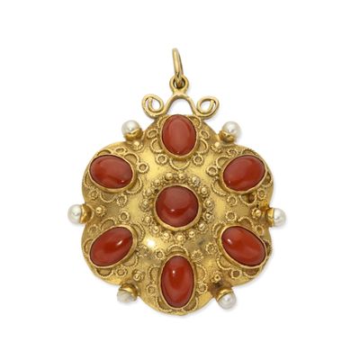a close up of a gold and coral pendant on a white background