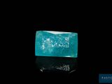 an emerald stone on a black surface with a black background