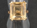une image représentant une bague ornée d'une topaze jaune sur un fond noir