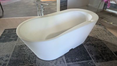 une grande baignoire blanche posée sur un tapis dans une salle de bains