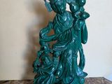 une statue verte représentant une femme tenant un bébé dans ses bras