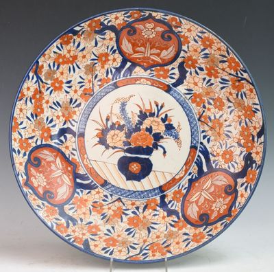 an orange and blue plate with a vase of flowers on it