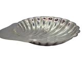 a silver shell shaped dish on a white background