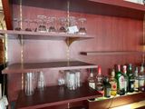a wooden shelf with wine glasses and bottles on it