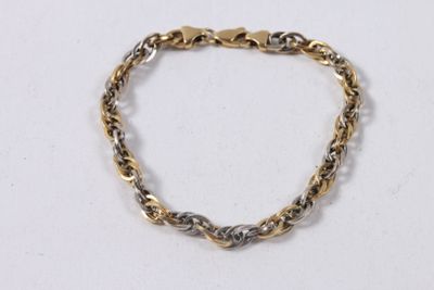 gros plan d'un bracelet en or et en argent sur une surface blanche