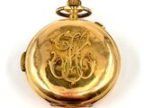 an image of a gold pocket watch with a monogram on it
