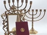 une menorah en or devant laquelle se trouve un livre rouge