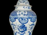 blue and white vase with a bird on top of it on a black background