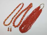 an assortment of orange beads and earrings on a white surface