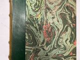 un vieux livre à la couverture verte posé sur une table blanche