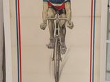 affiche représentant un homme à vélo, exposée devant une vitrine