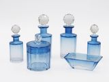 three blue glass bottles and a tray on a white surface