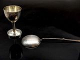une cuillère en argent et une tasse en argent posées sur une table noire