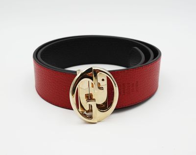 La ceinture est rouge et noire, avec une boucle dorée.