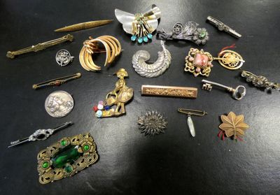 many different types of brooches and pins on the table
