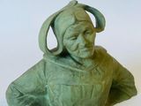 une statue verte représentant une femme coiffée d'un chapeau