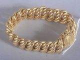 une image d'un gros plan d'un bracelet en or sur une surface blanche