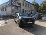 a black car parked in front of a building with a sign on it