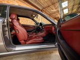 a silver car with red leather seats in a garage