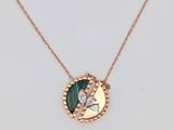 un collier en or orné d'un pendentif vert et blanc