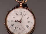 a gold pocket watch with roman numerals on the face