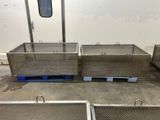 two large metal bins sitting on top of pallets in a warehouse