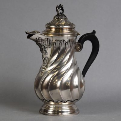 a silver coffee pot with a black handle on a gray surface